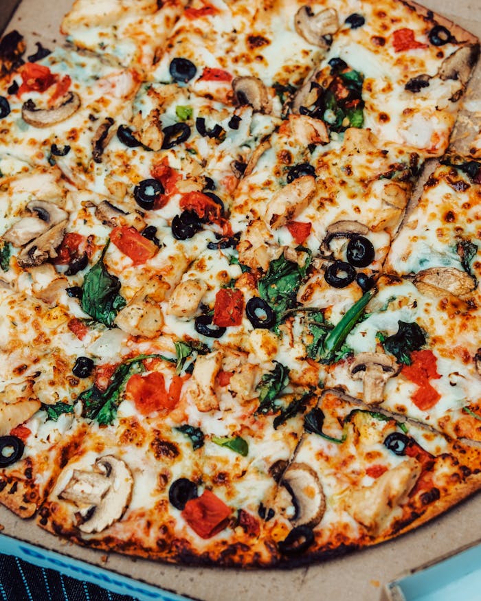 Closeup of a fresh vegetable and cheese pizza in a cardboard box, ready to eat.